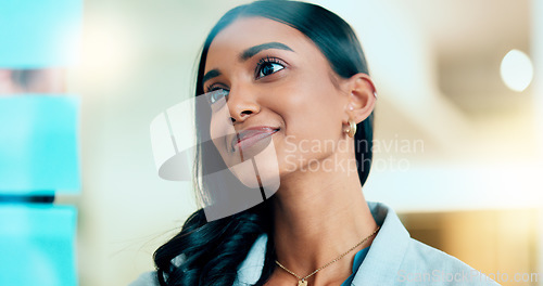 Image of Serious business woman brainstorm project ideas at a board with colorful sticky notes. Female marketing manager standing and writing business plan. Office worker thinking about corporate strategy.