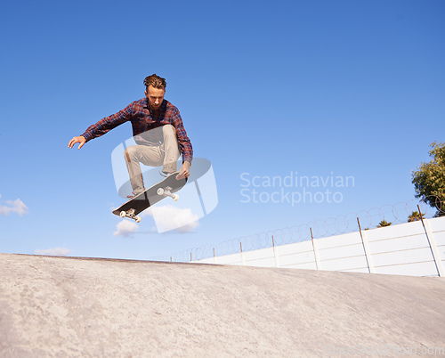 Image of Perfecting his tricks. A young man doing tricks on his skateboard at the skate park.