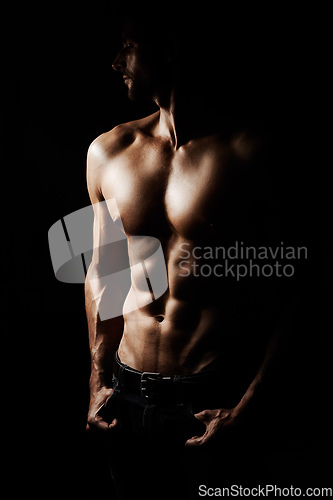 Image of Sculpted to perfection. Low-key image of a muscular young man on a black background.