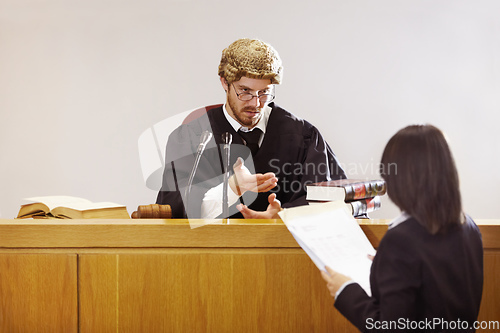 Image of Present your case.... Serious young judge sitting in the courtroom with a stern facial expression.