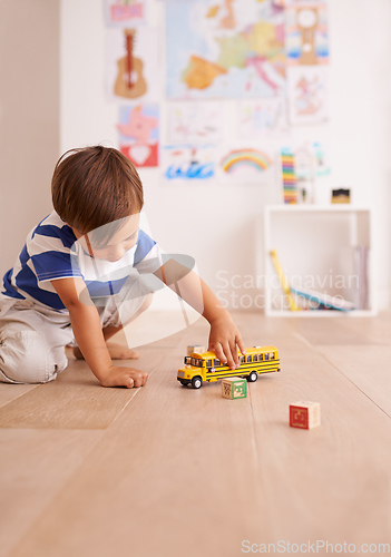 Image of The wheels on the bus go round and round. Shot of a cute little boy playing with his toys in his room.