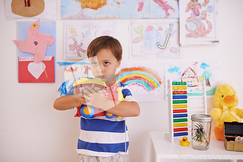 Image of No sharing. A young boy possessively clasping his toy truck to his chest.