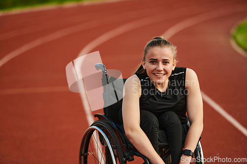 Image of A smiling woman with disablitiy sitting in a wheelchair and resting on the marathon track after training