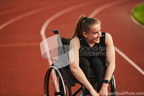 Image of A smiling woman with disablitiy sitting in a wheelchair and resting on the marathon track after training