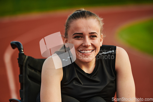 Image of A smiling woman with disablitiy sitting in a wheelchair and resting on the marathon track after training