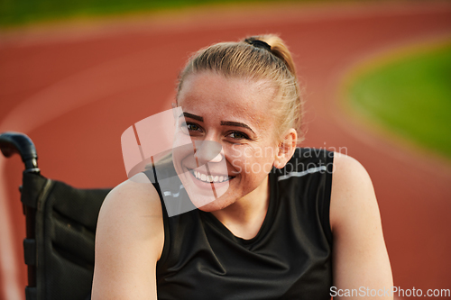 Image of A smiling woman with disablitiy sitting in a wheelchair and resting on the marathon track after training