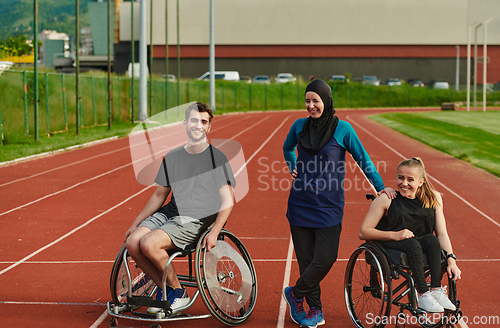 Image of A woman with a disability in a wheelchair talking after training with a woman wearing a hijab and a man in a wheelchair