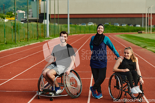 Image of A woman with a disability in a wheelchair talking after training with a woman wearing a hijab and a man in a wheelchair