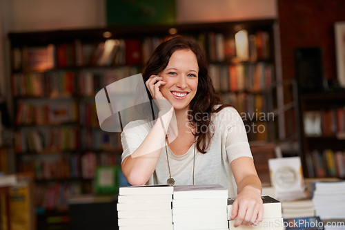 Image of Ive worked hard to make my bookstore successful. Portrait of a young woman leaning on stacks of books in a bookstore.