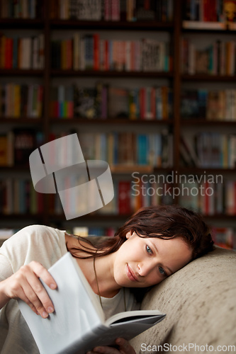 Image of In her own world. An attractive young woman relaxing on a sofa with a book - copy space.