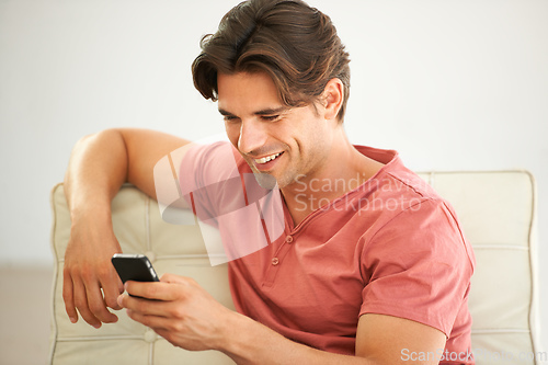 Image of Keeping in touch with the right people. A handsome young man reading a text message on his phone.