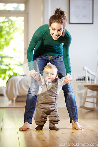 Image of Hes learning so fast. Smiling young mom helping her baby boy learn to walk.