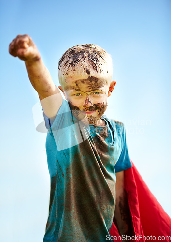 Image of A muddy superhero. A little boy dressed as a superhero and covered in mud.