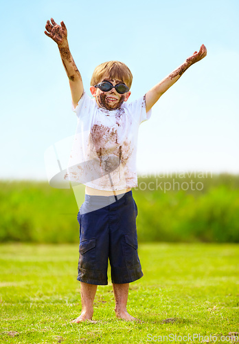 Image of A muddy superhero. A little boy dressed as a superhero and covered in mud.