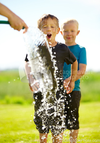 Image of They dont need a pool to cool off. Little boys getting wet by a hose pipe while outdoors.
