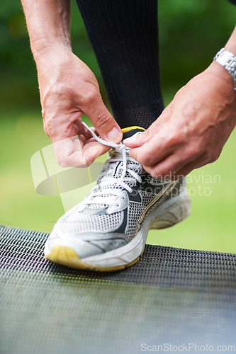 Image of Nothing worse than loose laces.... Cropped shot of a jogger resting his foot on a chair while tying his shoelace.