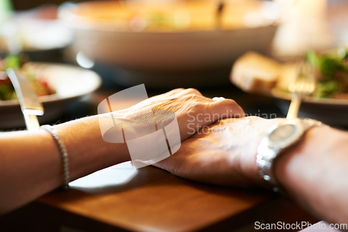 Image of We have each other. Cropped shot of a couple holding hands in prayer at the table before eating.