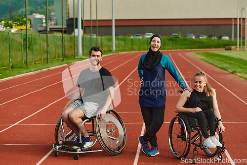 Image of A woman with a disability in a wheelchair talking after training with a woman wearing a hijab and a man in a wheelchair