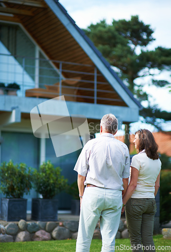 Image of Finally we can afford our dream home. Rearview shot of a mature couple standing hand-in-hand in front of their home.