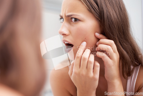 Image of What A pimple. A young woman looking shocked as she examines her skin.