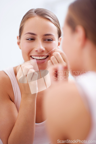 Image of Dental hygiene is a priority. A young woman flossing her teeth.