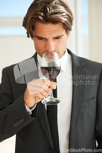 Image of Fruity yet playful. A handsome wine connoisseur enjoying a glass of red wine.