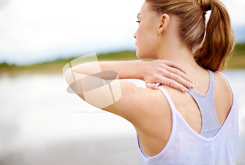 Image of This is so painful. Rearview shot of a young woman touching her shoulder.