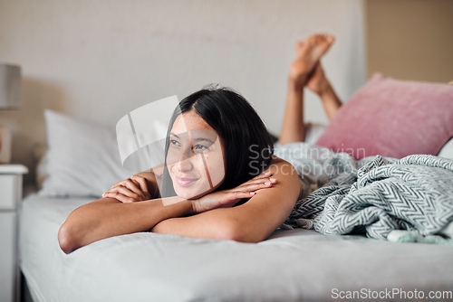 Image of Daydreams give us something to look forward to. Shot of a young woman enjoying a relaxing moment in bed at home.