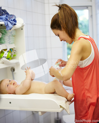 Image of Babysitting can be messy work. Cute young mom changing a babys diaper.