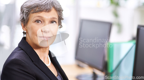 Image of Others in the office look up to her. Portrait of a mature woman sitting in an office.