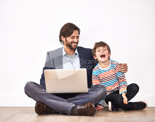 Image of Enjoying some funny online videos. A father and son sitting on the floor with a laptop.