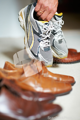 Image of Shoes for every occasion. Cropped shot of a man grabbing his running shoes from amongst his formal shoes.
