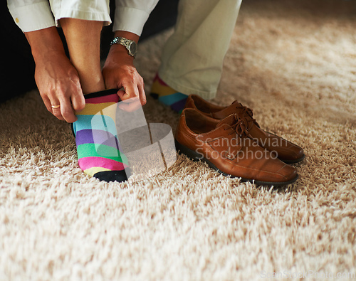 Image of Adding a little bit of fun to the outfit. Cropped shot of a man putting on colourful socks and loafers.