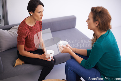 Image of Quick coffee discussion. Shot of two female professionals having a discussion in an informal office setting.