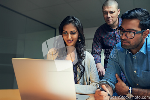 Image of They know how to handle business like pros. Cropped shot of a group of businesspeople working late on a laptop in an office.