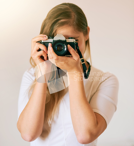 Image of Freezing this moment in time. Shot of an unrecognizable young woman taking a photo with her camera at home.