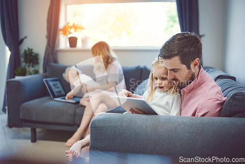 Image of They keep their home connected. Shot of an adorable little girl using a digital tablet with her father on the sofa at home.