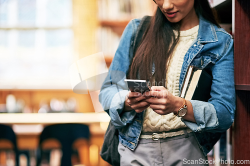 Image of Meet me in the library. Closeup shot of a university student texting on her cellphone in the library at campus.