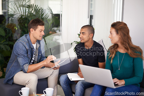 Image of Brainstorming some ideas. A team of young business professionals using technology in an informal meeting.