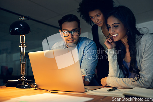 Image of Theyre all equally committed to accomplishing their deadlines. Cropped shot of a group of businesspeople working late on a laptop in an office.