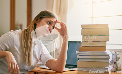 Image of This is what I get for procrastinating. Shot of a young woman looking overwhelmed by the pile of books on her desk.