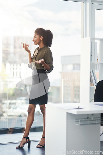 Image of Be bold and stand out above the rest. Full length shot of a young businesswoman standing in her office and busy talking on a smartphone.
