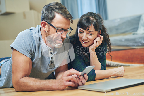 Image of All prepped and planned for moving day with mobile apps. Shot of a husband and wife using a mobile phone together on moving day.