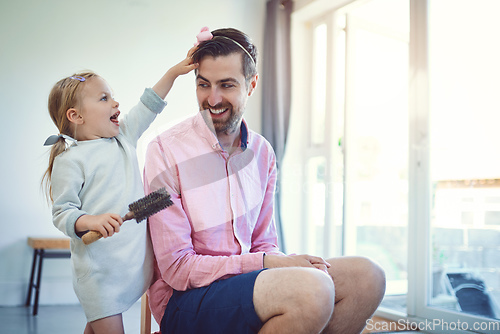 Image of Future hairstylist in the making. Shot of an adorable little girl brushing her fathers hair at home.