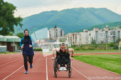 Image of A Muslim woman in a burqa running together with a woman in a wheelchair on the marathon course, preparing for future competitions.