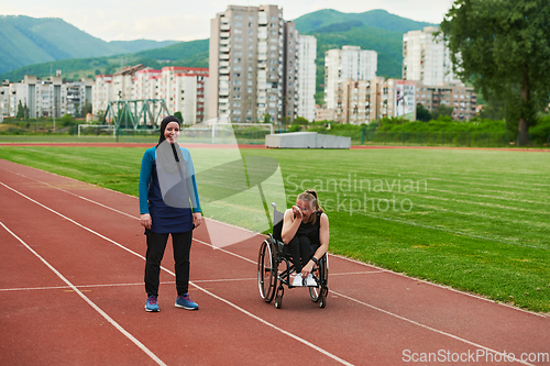 Image of A Muslim woman in a burqa running together with a woman in a wheelchair on the marathon course, preparing for future competitions.