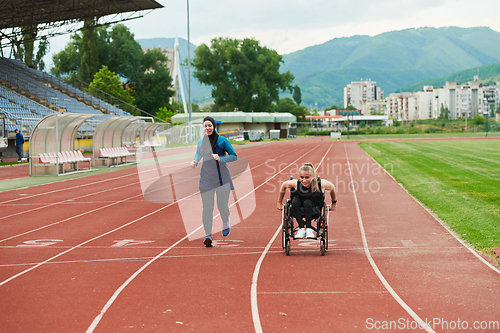 Image of A Muslim woman in a burqa running together with a woman in a wheelchair on the marathon course, preparing for future competitions.