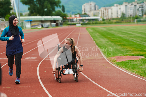 Image of A Muslim woman in a burqa running together with a woman in a wheelchair on the marathon course, preparing for future competitions.