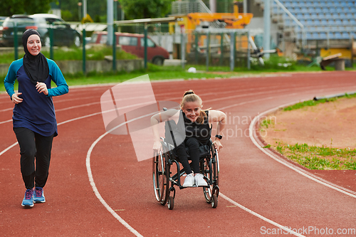 Image of A Muslim woman in a burqa running together with a woman in a wheelchair on the marathon course, preparing for future competitions.