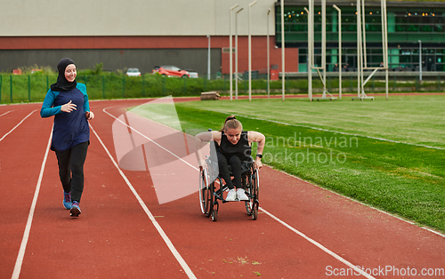 Image of A Muslim woman in a burqa running together with a woman in a wheelchair on the marathon course, preparing for future competitions.